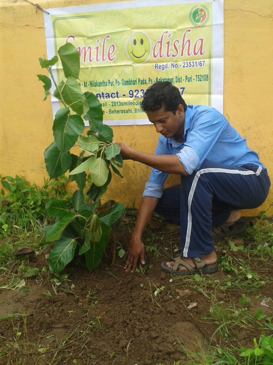 Smile Odisha volunteer planting a sapling as part of the plantation programme